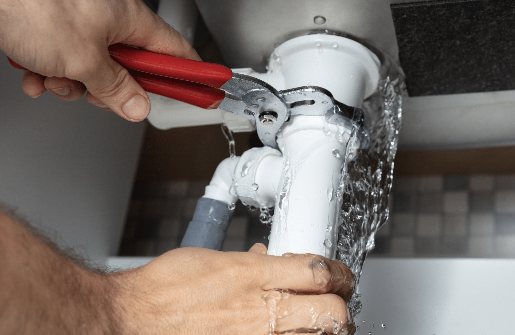 Emergency Plumber Repairing Gushing P-Trap and Pressurized Supply Lines Under Sink